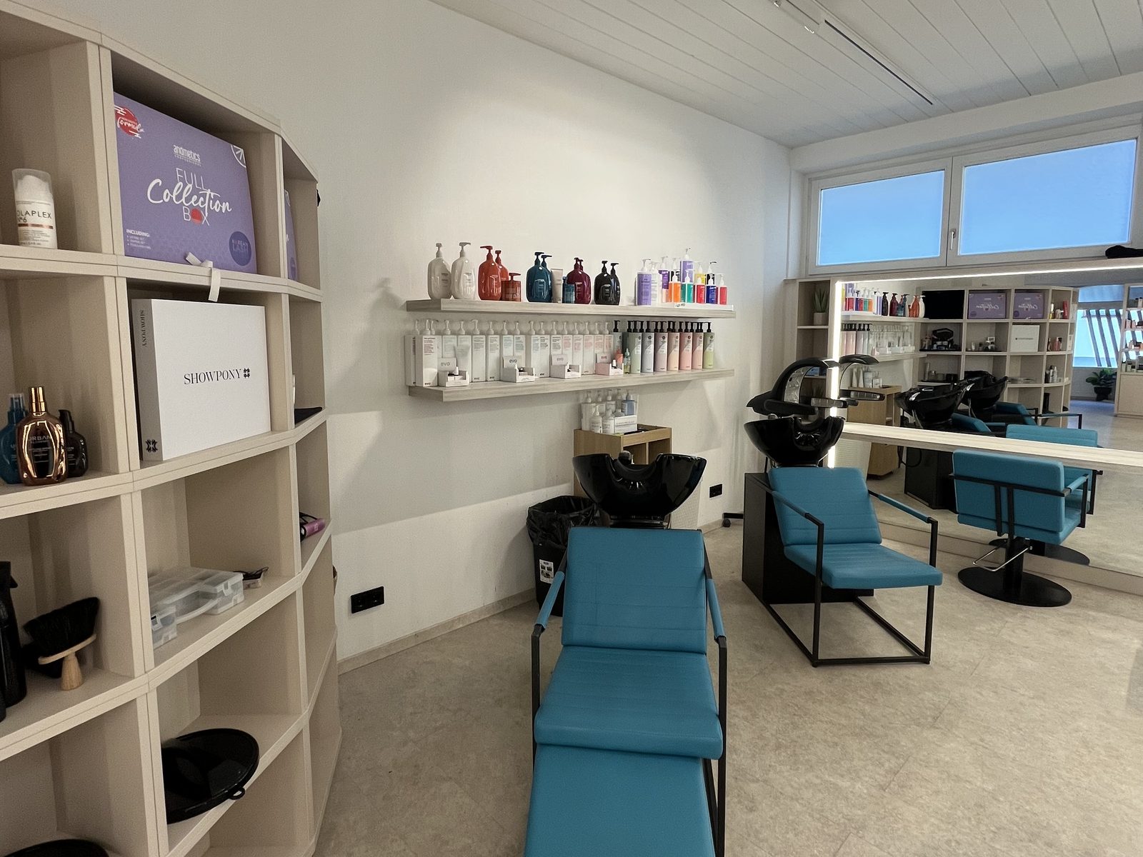 Washing area at HAIRLODGE Ellmau with comfortable reclining wash chairs and shelves full of shampoos and treatments.