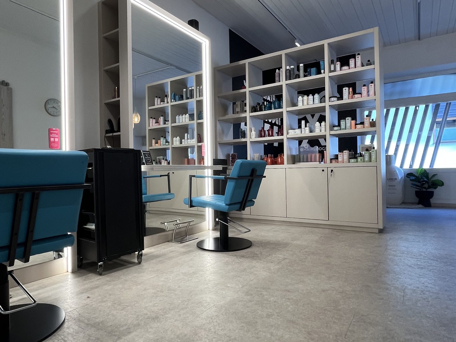 Styling area at HAIRLODGE Ellmau with mirror stations and the HAIRLODGE-branded shelving wall in the background.