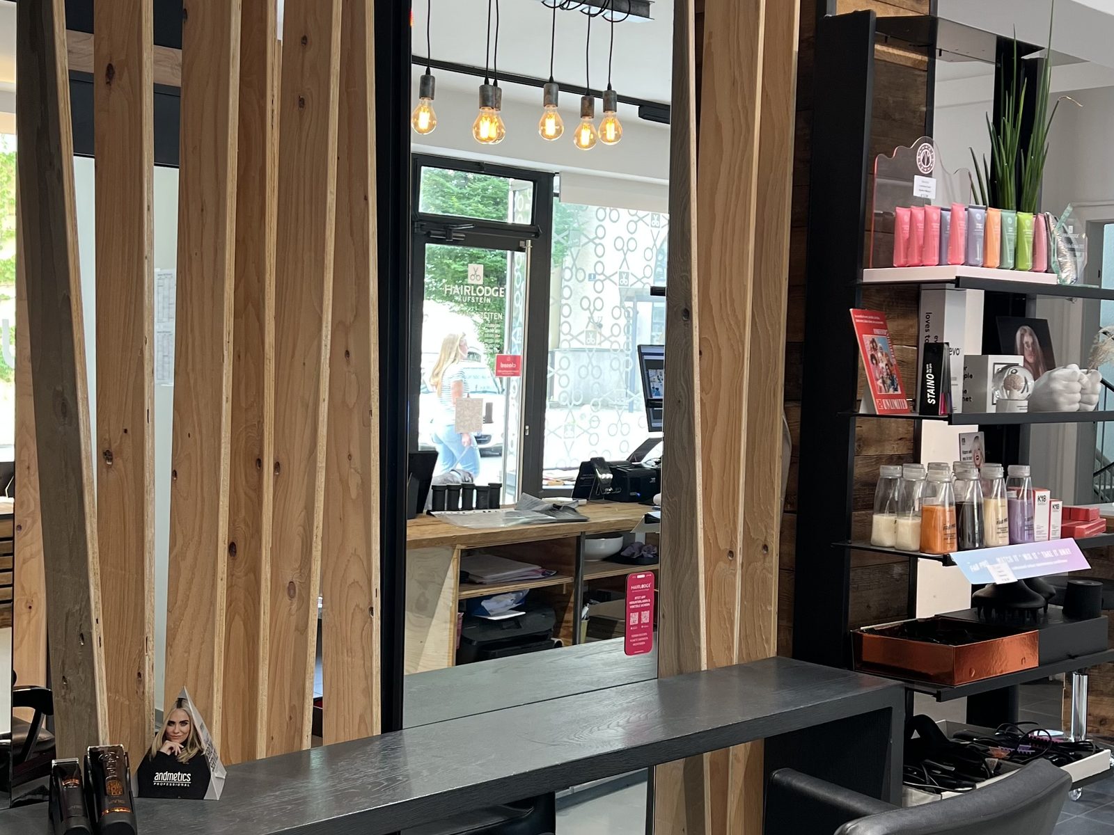 Styling station at HAIRLODGE Kufstein behind a wooden slat wall, with mirror and pendant lamps.